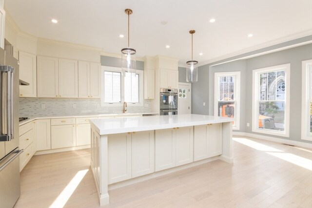 kitchen featuring appliances with stainless steel finishes, a center island, decorative light fixtures, and tasteful backsplash