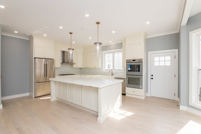 kitchen with appliances with stainless steel finishes, a center island, hanging light fixtures, and sink