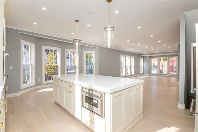 kitchen featuring a wealth of natural light, a kitchen island, hanging light fixtures, and oven