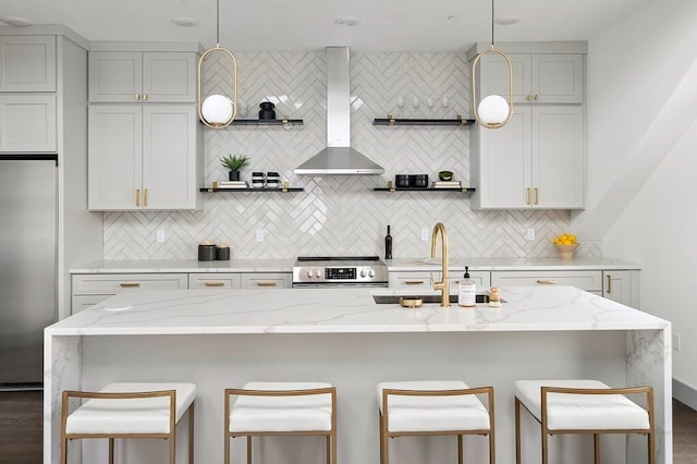 kitchen with stainless steel appliances, light stone countertops, dark hardwood / wood-style floors, a center island with sink, and wall chimney range hood