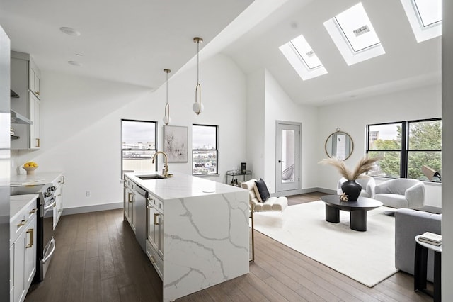 kitchen with stainless steel range with electric stovetop, light stone counters, an island with sink, hanging light fixtures, and dark wood-type flooring