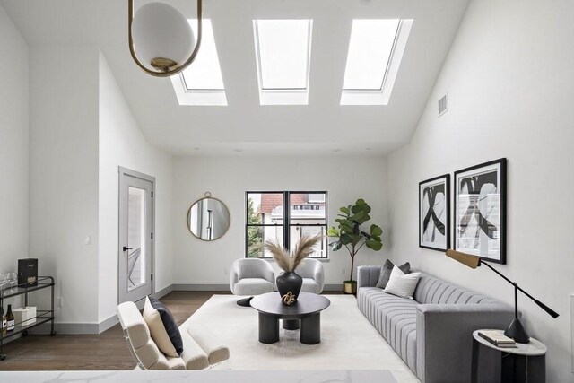 living room with high vaulted ceiling, a skylight, and wood-type flooring