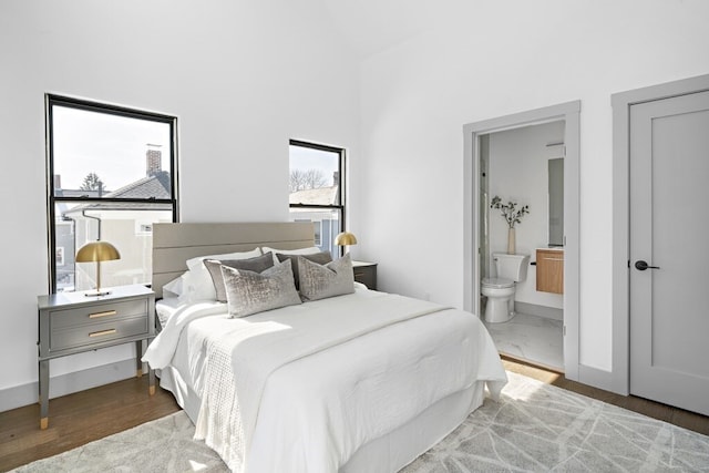 bedroom featuring multiple windows, wood-type flooring, and connected bathroom