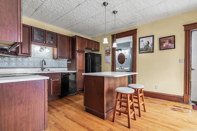 kitchen with glass insert cabinets, a center island, light countertops, and black appliances