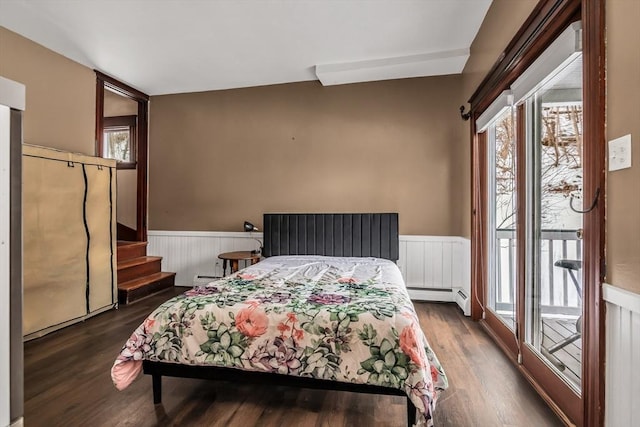 bedroom with a wainscoted wall, access to outside, multiple windows, and dark wood-style floors