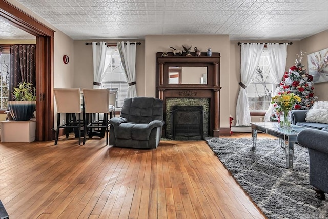 living area featuring a fireplace, wood finished floors, and an ornate ceiling