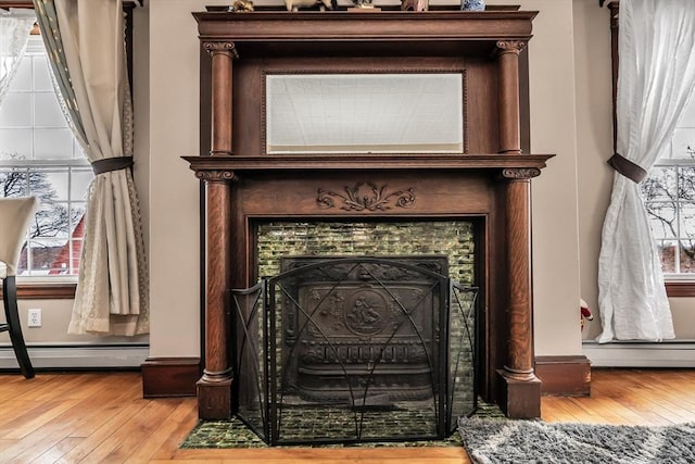 room details featuring a baseboard radiator, a fireplace, and wood finished floors