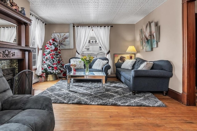 living room with a fireplace, baseboards, and wood finished floors