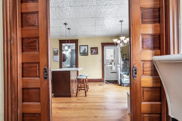 interior space with hanging light fixtures, light wood-style floors, baseboards, and light countertops