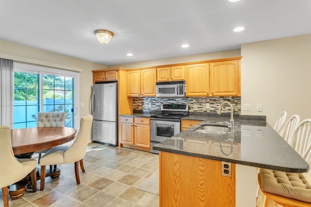 kitchen with tasteful backsplash, sink, kitchen peninsula, a kitchen breakfast bar, and stainless steel appliances