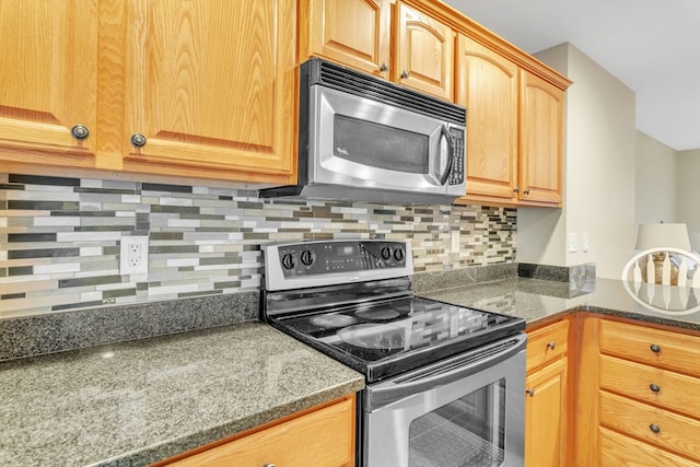 kitchen featuring dark stone counters, stainless steel appliances, and backsplash