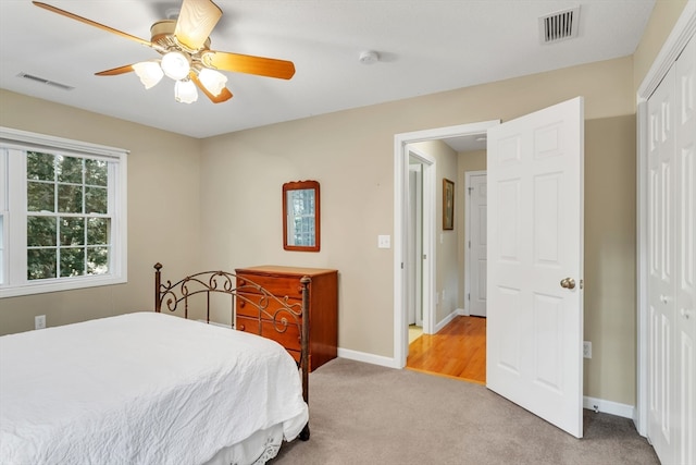 bedroom with ceiling fan, light colored carpet, and a closet