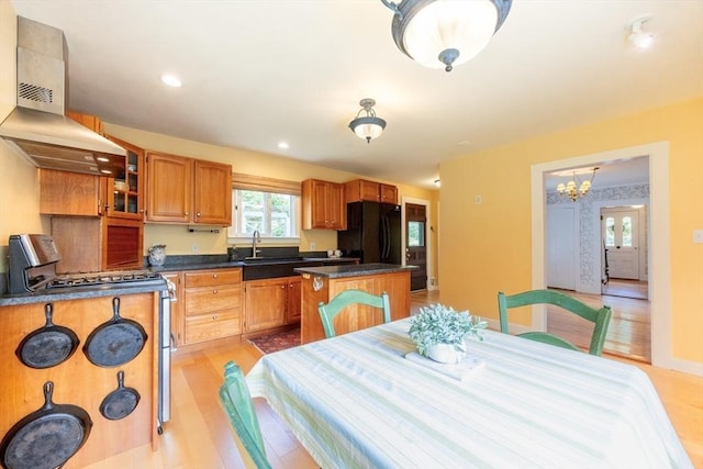 75 Union St, Holliston, MA 01746 - kitchen featuring wall chimney range hood, gas range, freestanding refrigerator, a center island, and light wood-type flooring