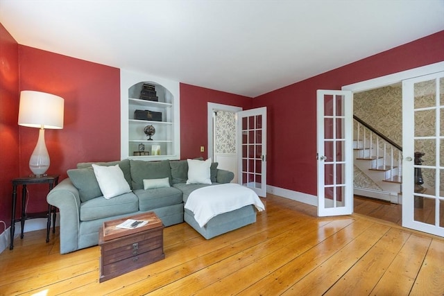 75 Union St, Holliston, MA 01746 - living room featuring french doors, hardwood / wood-style floors, built in shelves, a baseboard radiator, and stairs