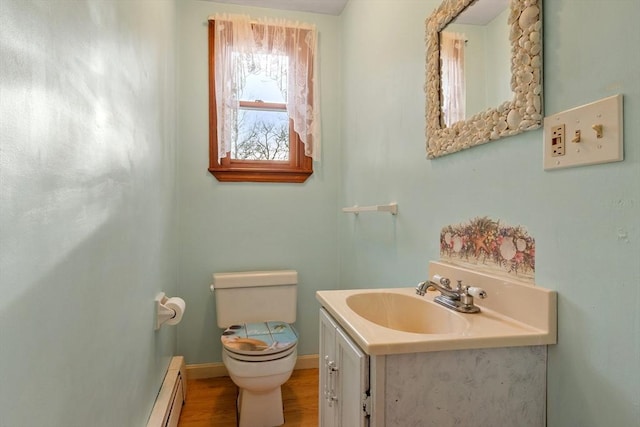 half bathroom with vanity, wood finished floors, baseboards, toilet, and baseboard heating