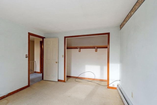 unfurnished bedroom featuring a baseboard heating unit, carpet, a closet, and baseboards