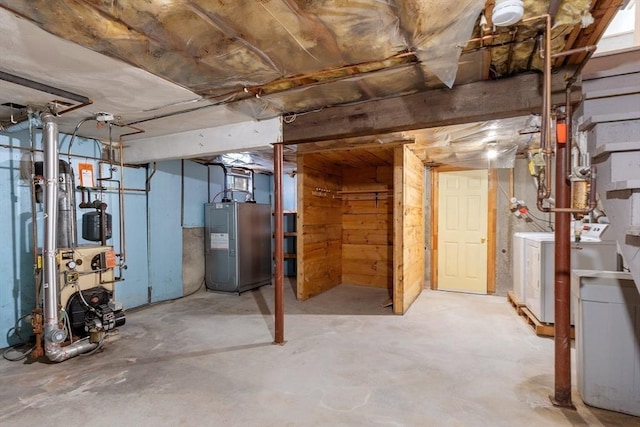 unfinished basement with electric water heater, a heating unit, and washing machine and clothes dryer