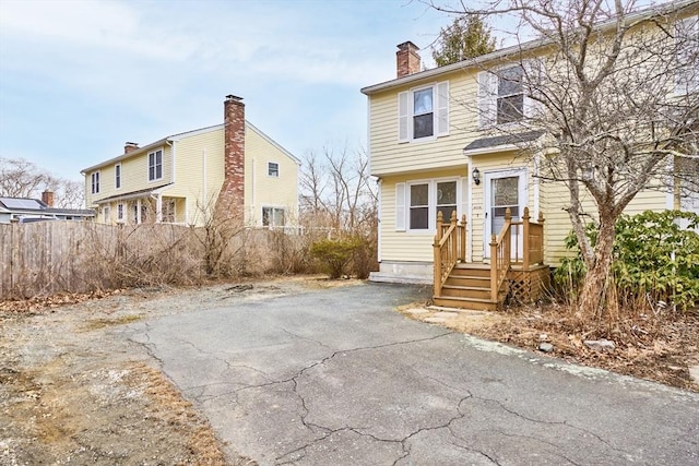 view of front of home with fence, driveway, and a chimney