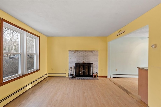 unfurnished living room with a fireplace, a baseboard heating unit, and wood finished floors