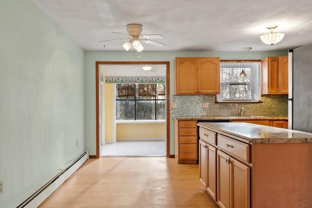 kitchen with light wood-style flooring, a sink, backsplash, a baseboard radiator, and hanging light fixtures