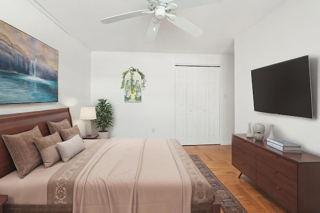 bedroom with light parquet floors, ceiling fan, and a closet