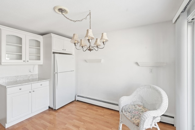 kitchen with baseboard heating, light hardwood / wood-style floors, white cabinetry, and white fridge