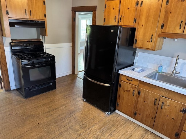 252-256 Billings St, Quincy, MA 02169 - kitchen featuring black appliances, under cabinet range hood, tile countertops, light wood-style flooring, and a wainscoted wall