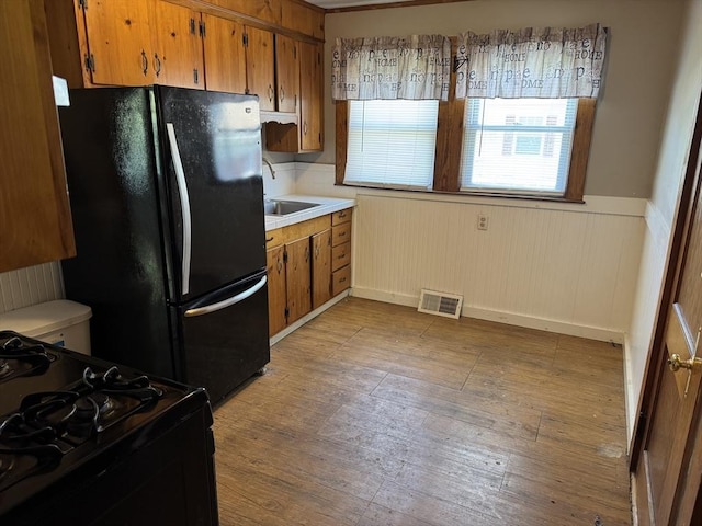 252-256 Billings St, Quincy, MA 02169 - kitchen with black appliances, brown cabinets, light wood-style flooring, a sink, and wainscoting