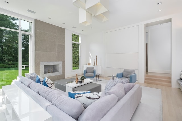 living room with a healthy amount of sunlight, a tile fireplace, and light wood-type flooring