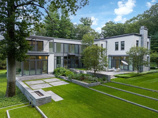 rear view of house featuring a patio area, a sunroom, and a yard