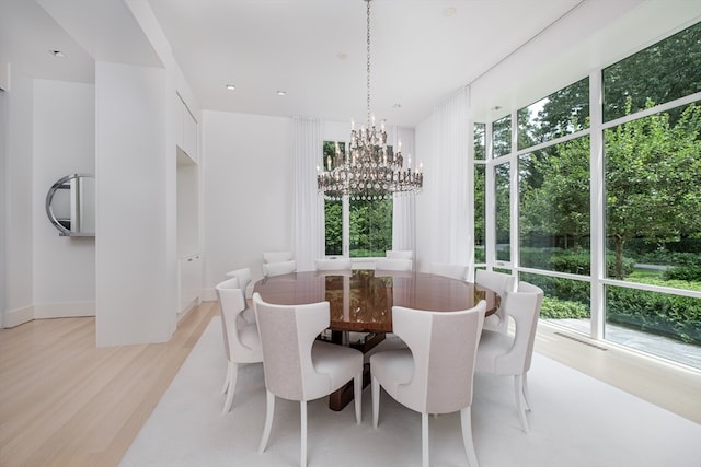 dining space with plenty of natural light, light hardwood / wood-style floors, and a notable chandelier