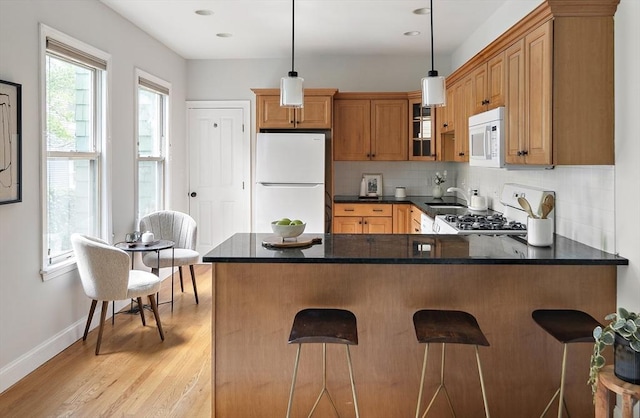 28 Summer St Unit 1, Somerville, MA 02143 - kitchen featuring white appliances, decorative backsplash, a peninsula, light wood-style floors, and baseboards