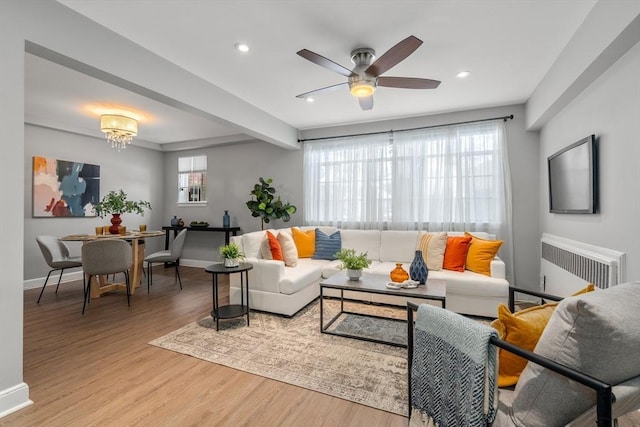 living room with hardwood / wood-style flooring, ceiling fan with notable chandelier, radiator, and a wealth of natural light