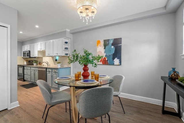 dining space with hardwood / wood-style floors, crown molding, a chandelier, and sink