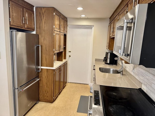 kitchen with a sink, light countertops, appliances with stainless steel finishes, recessed lighting, and light floors