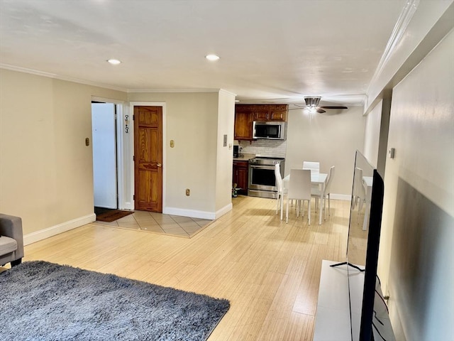 living area with a ceiling fan, baseboards, and ornamental molding
