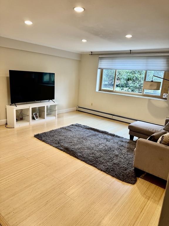 living area featuring recessed lighting, a baseboard radiator, baseboards, and wood finished floors