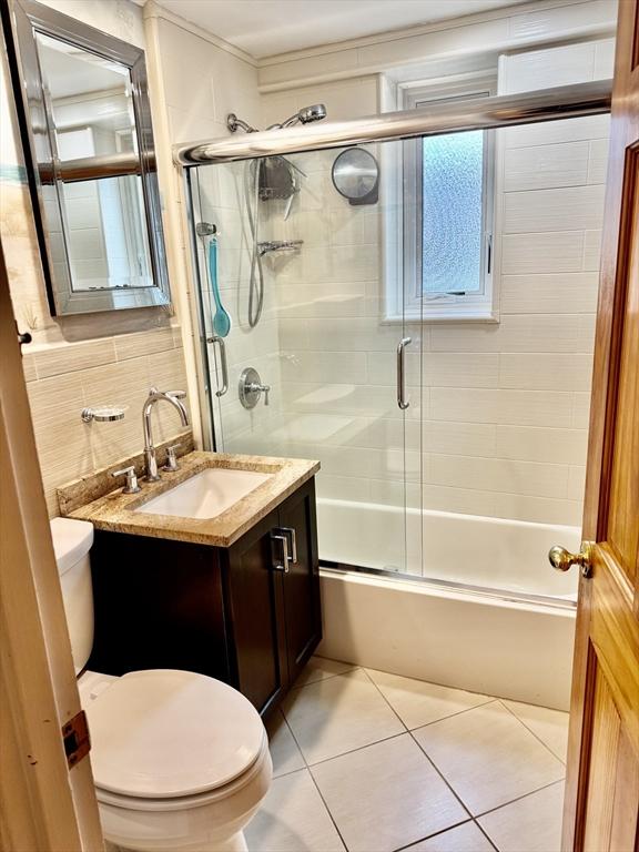 bathroom featuring tile patterned floors, shower / bath combination with glass door, vanity, and toilet