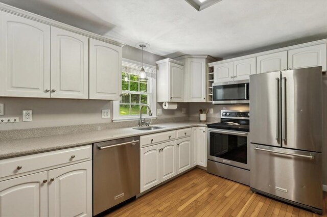 24 S Loomis St, Southwick, MA 01077 - kitchen featuring stainless steel appliances, a sink, light wood finished floors, pendant lighting, and white cabinets