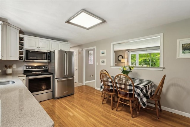 24 S Loomis St, Southwick, MA 01077 - kitchen with appliances with stainless steel finishes, white cabinets, light wood-style flooring, light countertops, and a sink