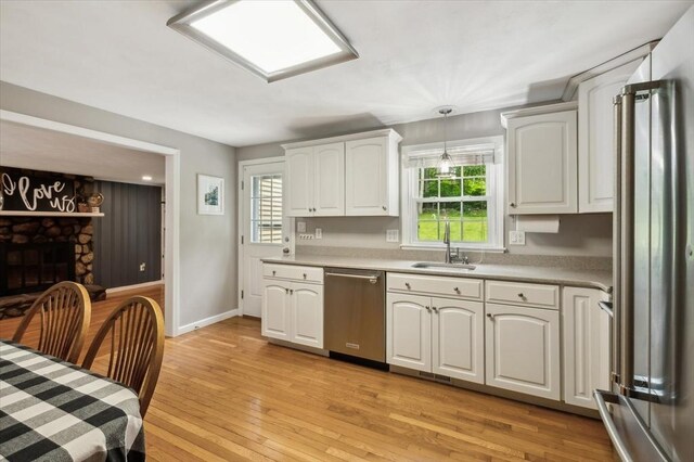 24 S Loomis St, Southwick, MA 01077 - kitchen featuring stainless steel appliances, a sink, light wood finished floors, white cabinetry, and hanging light fixtures