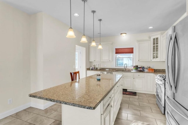 kitchen with appliances with stainless steel finishes, stone countertops, decorative light fixtures, white cabinetry, and a center island