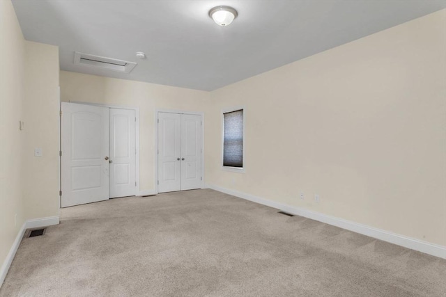 unfurnished bedroom featuring multiple closets and light carpet