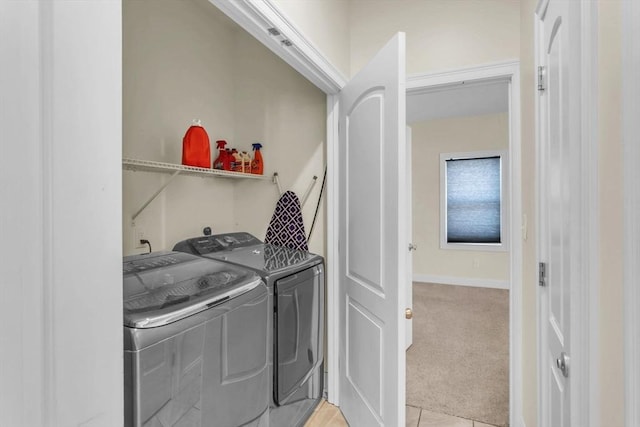 clothes washing area featuring light carpet and washer and dryer