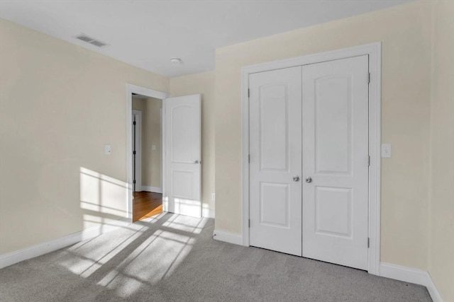 unfurnished bedroom featuring light carpet and a closet