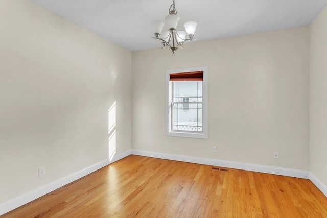 empty room featuring a chandelier and light wood-type flooring