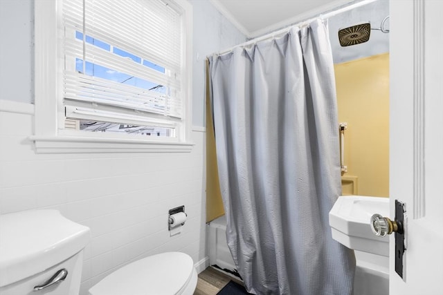 bathroom featuring crown molding, tile walls, toilet, and shower / bath combo with shower curtain