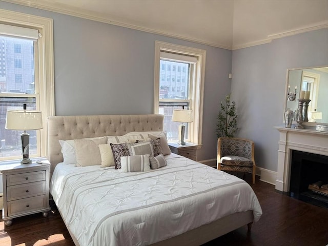 bedroom featuring dark wood-style flooring, ornamental molding, baseboards, and a fireplace