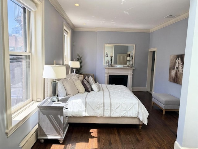 bedroom featuring a baseboard heating unit, dark wood finished floors, multiple windows, ornamental molding, and a fireplace