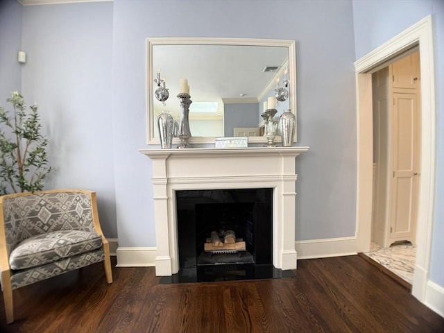 living area featuring baseboards, wood finished floors, a fireplace with flush hearth, and crown molding